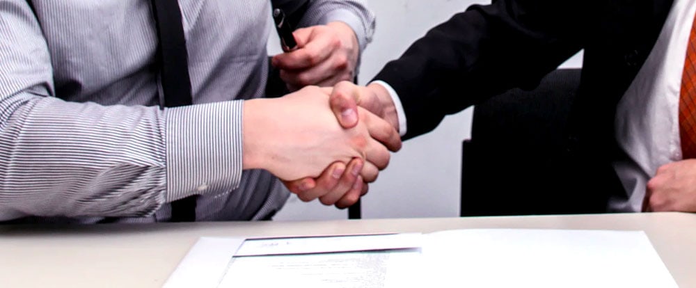 Two businessmen shaking hands over a contract.