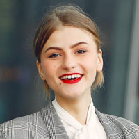 A stylish woman wearing red lipstick and a plaid jacket.